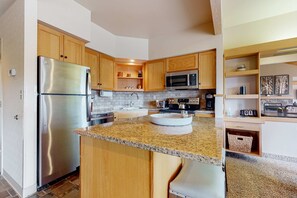 Una cocina con armarios de madera, electrodomésticos de acero inoxidable, encimeras de granito y una isla integrada.