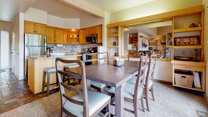 A modern kitchen with wooden cabinets, stainless steel appliances, and a central island with bar stools. - Charming waterfront condo with pool, tennis, hot tub, balcony, & W&D (Eagle Crest)