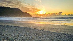 A beach with pebbles, a sunset, and a forested hill. - Cozy Seaside Bungalow, Brand New Hot Tub, Fast WiFi & W&D - Walk to the Beach (Seaside)