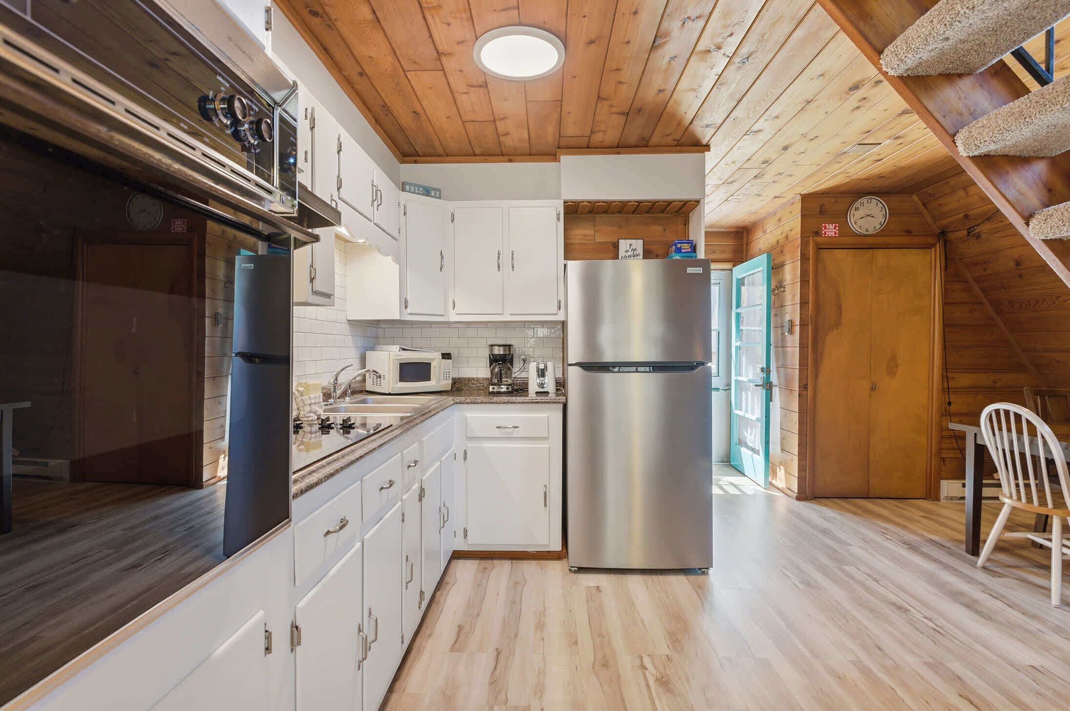 A kitchen with white cabinets, a stainless steel refrigerator, a microwave, and a coffee maker.
