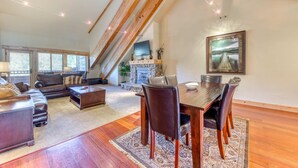Un salón espacioso con una mesa de comedor de madera, sillones de cuero, una chimenea y un ventanal grande.