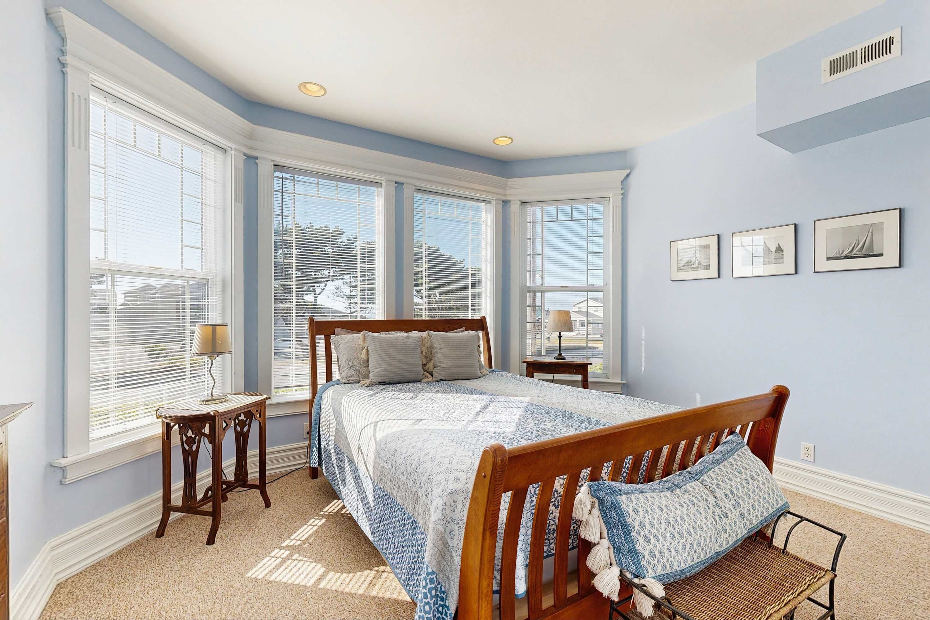 Une chambre à coucher avec un grand lit, une table de chevet, une chaise et une fenêtre avec des stores.