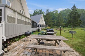 A patio area with a grill, picnic table, and outdoor seating. - Juniper Presents: Chalet #76 3BR Chalet Nr Beach & Resort Amenities (Stevensville)