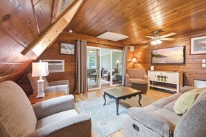 A cozy room with a wooden ceiling, a ceiling fan, a TV, and a view of the outdoors through a sliding glass door. - Juniper Presents Chalet #81: Nr Pool, Tennis & Resort Amenities (Stevensville)