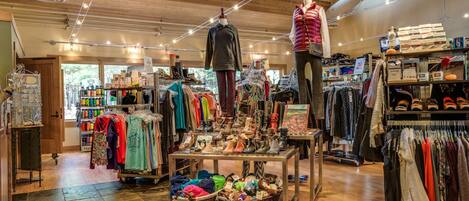 A clothing store with racks of clothes, a mannequin, and a table with shoes.