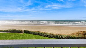 Vista de una playa con césped y una valla de madera.