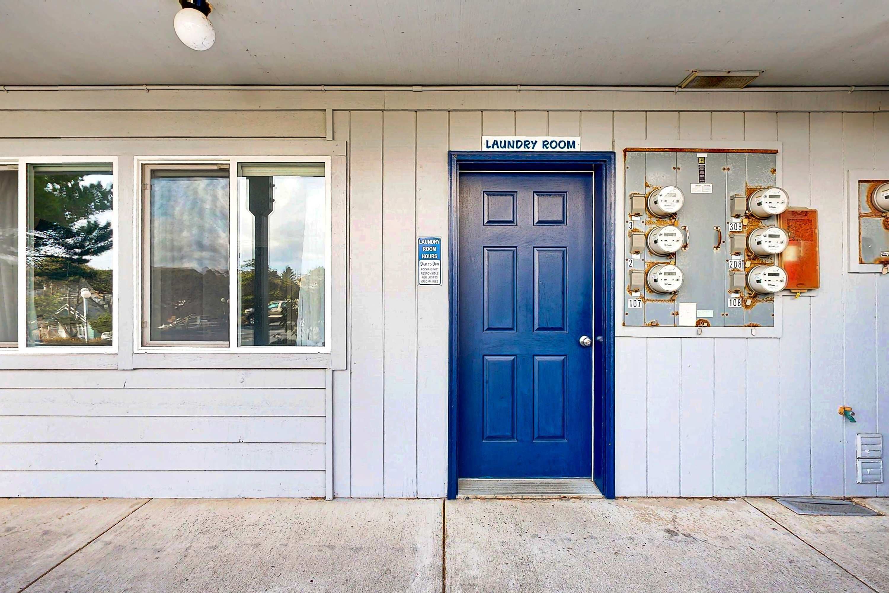 A building with a blue door labeled 'Laundry Room,' windows, and electrical panels.