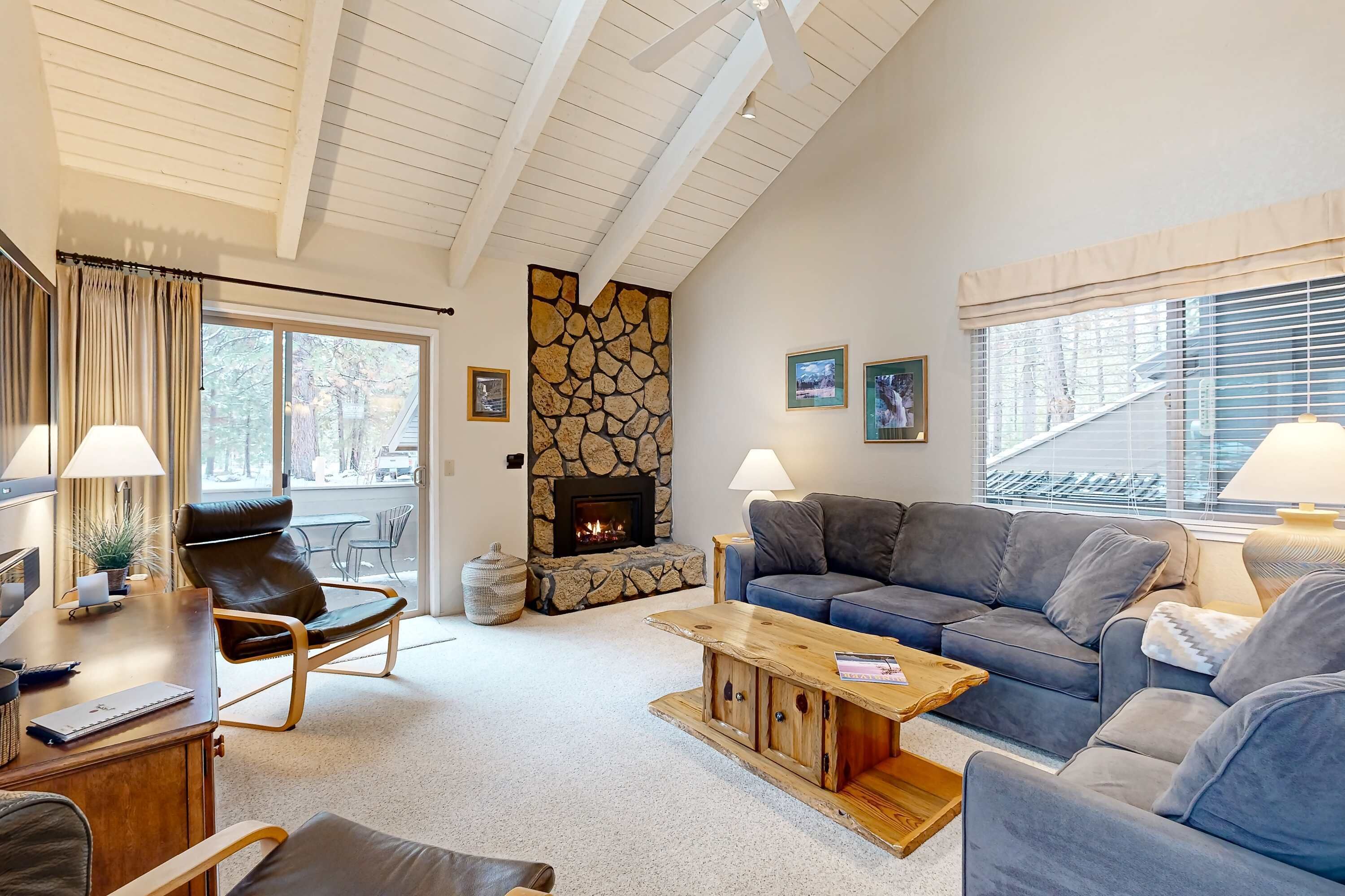 A living room with a fireplace, a sofa, a coffee table, and a desk with a lamp.