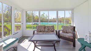 Une véranda donnant sur une piscine, avec des meubles en osier et une petite table.