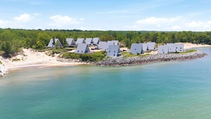 Une station balnéaire dotée de bâtiments modernes à toits triangulaires, d’une digue rocheuse et d’une plage de sable.