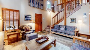 Un salon spacieux avec un escalier en bois, un canapé, une table basse et une cheminée.