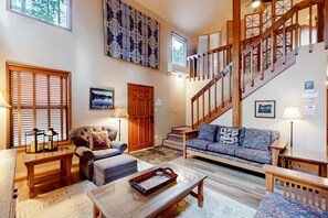 Ein geräumiges Wohnzimmer mit einer Holztreppe, einem Sofa, einem Couchtisch und einem Kamin.