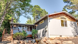 A two-story house with a stone retaining wall, a wooden staircase, and a small garden area. - Adorable dog-friendly home with gas grill, gas fireplace & private back patio (Manzanita)