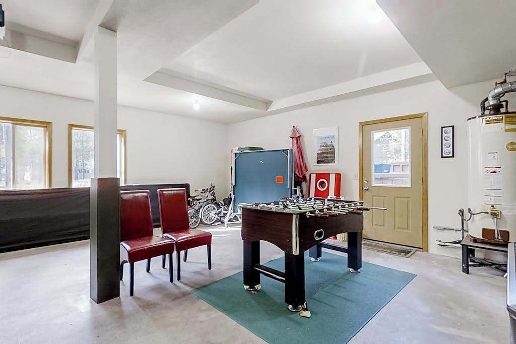A room with a foosball table, red chairs, a blue door, and a window with a view.