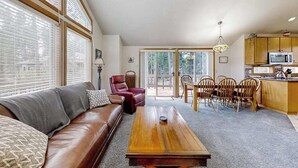 Uma sala de estar com sofá, mesa de centro e área de jantar com cadeiras e mesa.