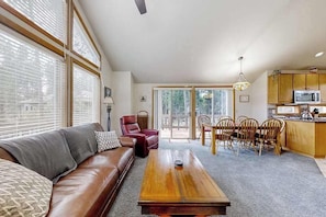 A living room with a sofa, coffee table, and dining area with chairs and a table.