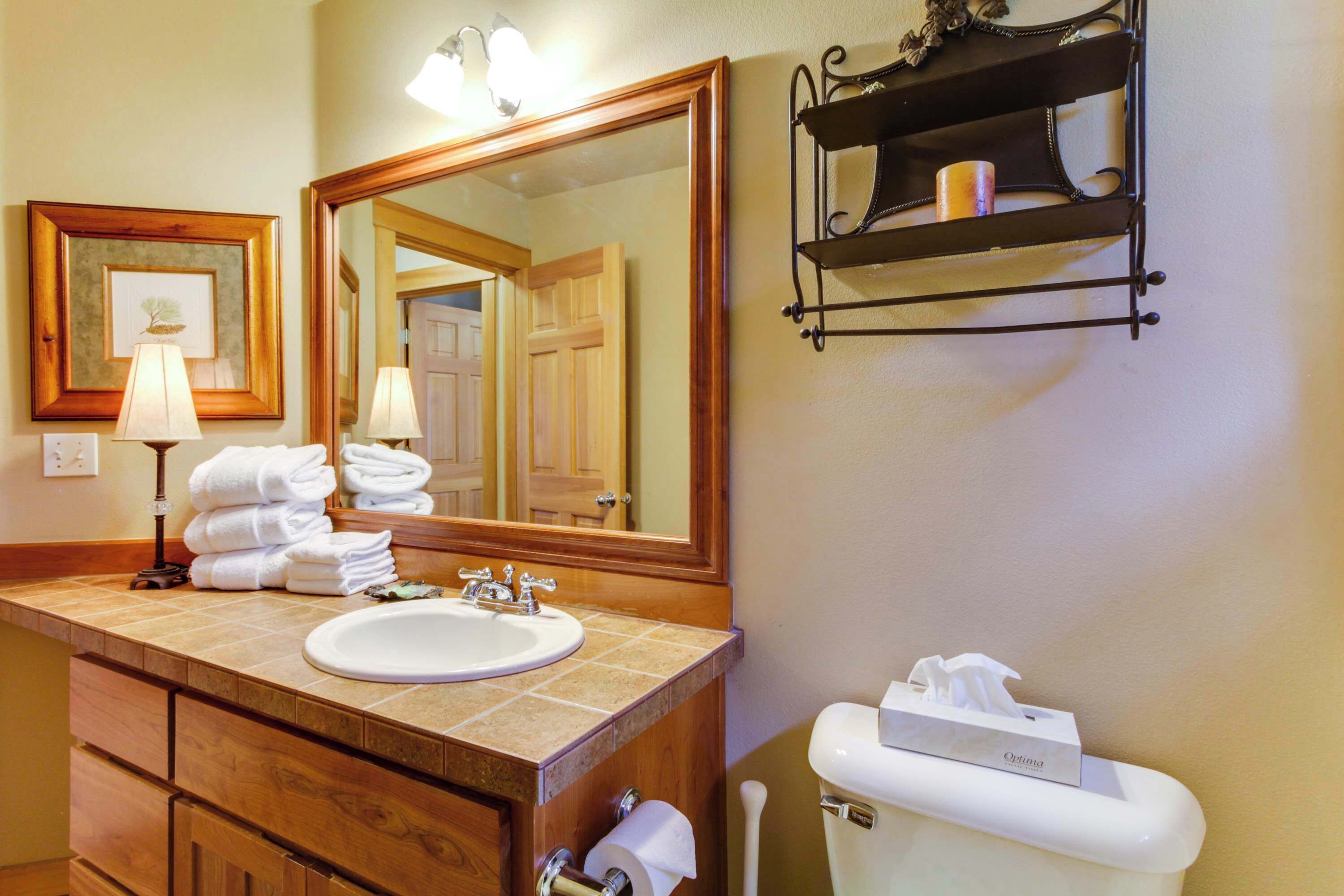 A bathroom with a sink, mirror, towel rack, and toilet paper holder.