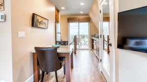 A modern kitchen with a dining area, a large window, and a flat-screen TV. - Lovely studio guesthouse with ocean views, outdoor deck & washer/dryer (Warrenton)