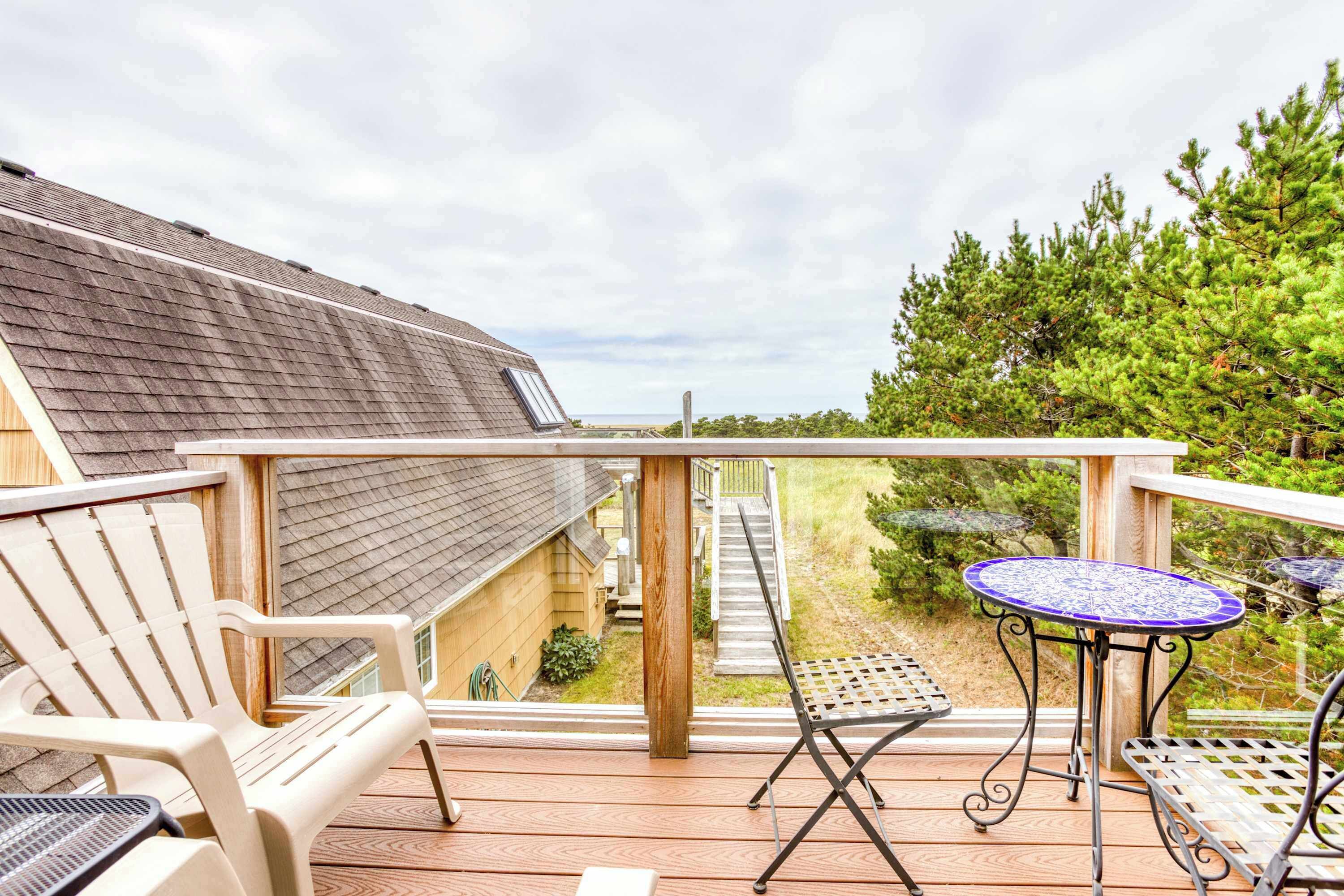 Une terrasse en bois avec une table et des chaises, donnant sur un jardin, et une maison en bois.