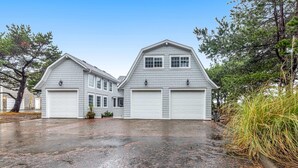 A two-story house with a garage, surrounded by trees and a wet driveway. - Lovely studio guesthouse with ocean views, outdoor deck & washer/dryer (Warrenton)