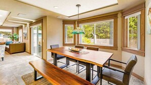A dining area with a wooden table, six chairs, a bench, and a hanging light fixture.