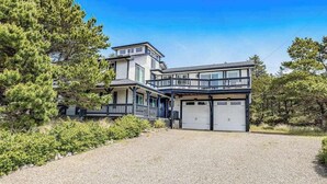 A two-story house with a covered porch, a garage, and a gravel driveway.