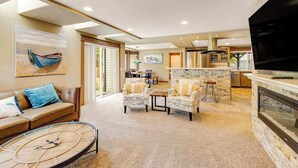A spacious living area with a sofa, armchairs, a coffee table, and a fireplace.