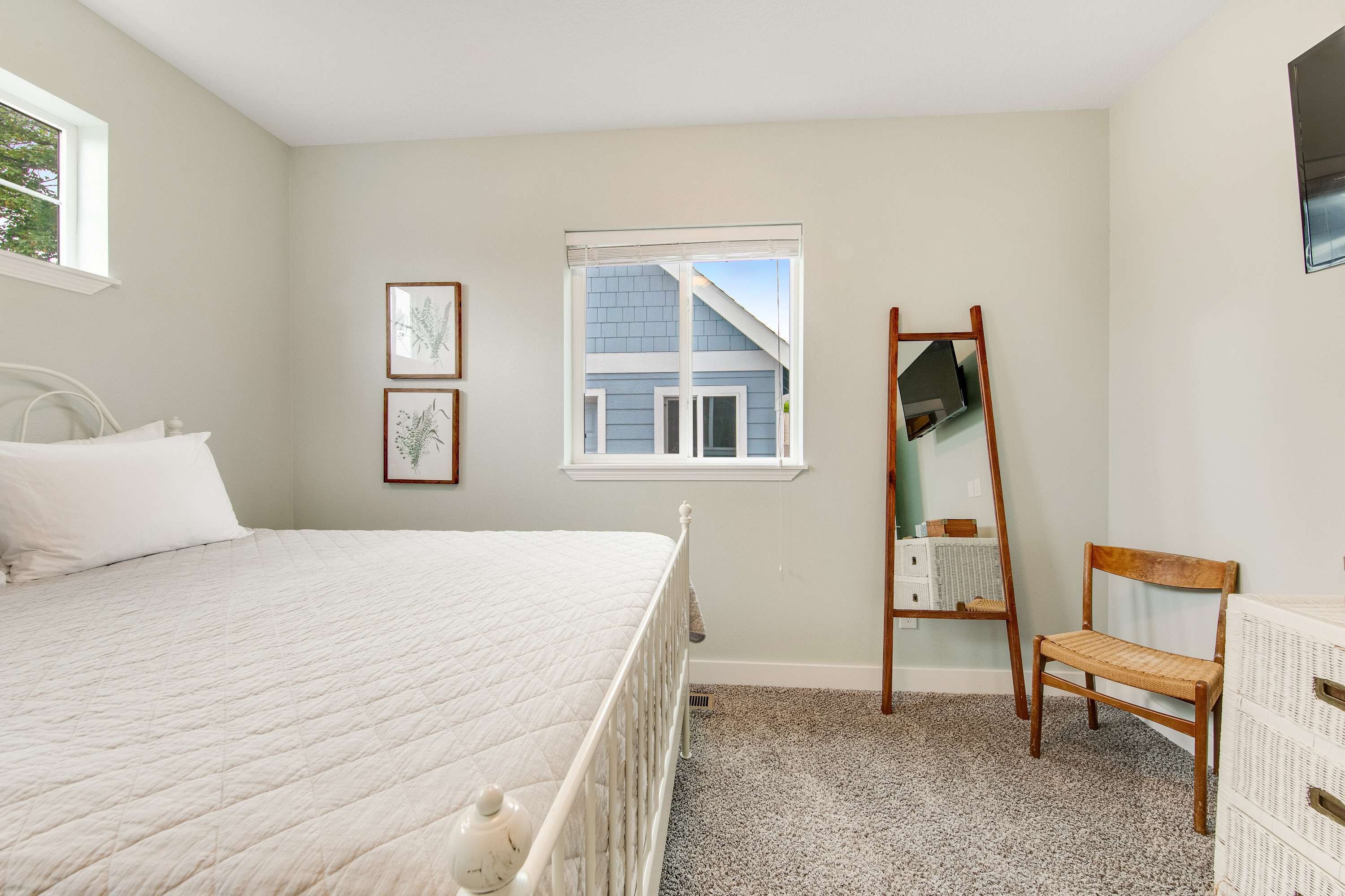 A bedroom with a bed, a window, a mirror, and a chair.