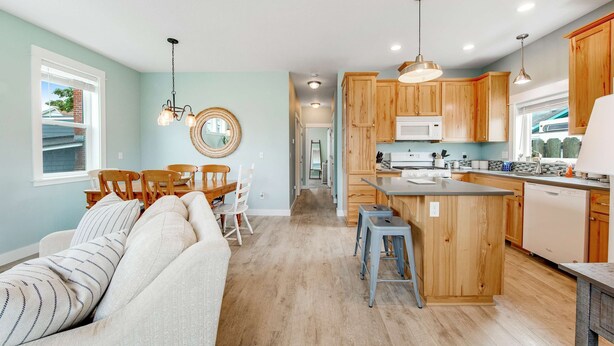 A modern kitchen with wooden cabinets, a central island, and a dining area with a sofa and chairs. - Newer home 1 block from the beach & Prom with fireplace & deck - 2 dogs OK (Seaside)