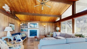 Een houten interieur met een bank, stoelen, een open haard en een televisie.
