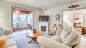 Een gezellige woonkamer met een open haard, comfortabele zitplaatsen, een televisie en een eethoek.