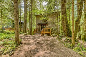 A cabin with a wooden deck, a staircase, and a 'Welcome' sign. - Serene Cottage on the River with Firepit, Deck, and Bunk Room (Rhododendron)