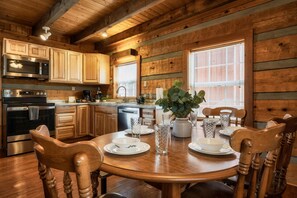 A wooden interior with a kitchen, dining table, chairs, and a potted plant. - Beautiful Cabin, Perfect Location. Book Now! Minutes From Town! (Sevierville)