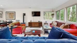 Un salon moderne comprenant un canapé, un fauteuil, une table basse et un téléviseur fixé au mur.