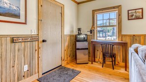 A compact room with a wooden door, a small kitchenette, a window with a view, a chair, and a couch. - 2-story dog-friendly cabin near White Salmon River with mtn views, courtyard, AC (White Salmon)