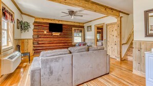 A log cabin interior with a sofa, wooden walls, a ceiling fan, and a staircase. - 2-story dog-friendly cabin near White Salmon River with mtn views, courtyard, AC (White Salmon)