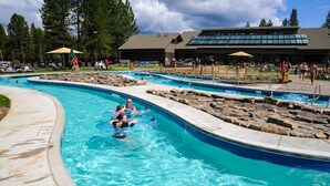 A swimming pool with multiple lanes, a lifeguard tower, and a building with large windows in the background. - Cozy Sunriver Home with Hot Tub, Wood Stove, SHARC Passes (Sunriver)