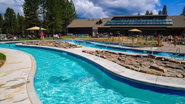 Une piscine avec plusieurs couloirs de nage, un poste de surveillance pour les sauveteurs et un bâtiment avec une grande fenêtre en arrière-plan.