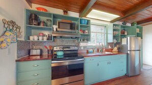 A kitchen with teal cabinetry, stainless steel appliances, and a wooden floor.