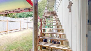 A wooden staircase leading to a porch with a white exterior wall and a cross decoration.