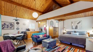 Een gezellige woonkamer met een bank, een voetenbankje en een bed met hoofdbord.