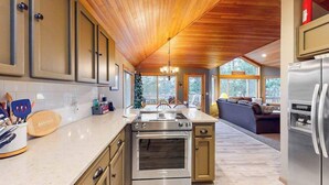 A kitchen with wooden cabinets, a stainless steel stove, and a refrigerator. - Inviting house with hot tub, game tables, bikes, & partial mountain view (Sunriver)