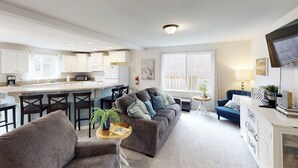 Un salon moderne avec un canapé, des fauteuils, une table basse et un téléviseur.