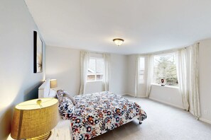 Ein Schlafzimmer mit einem Bett, einer Lampe und einem Fenster mit Vorhängen.