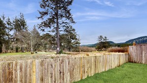 Une clôture en bois, de l’herbe verte et des arbres dans un environnement naturel.