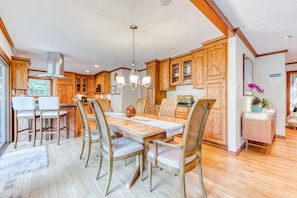 A spacious kitchen with wooden cabinets, a dining table with chairs, and a chandelier.