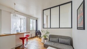 Ein modernes Wohnzimmer mit einem grauen Sofa, einem roten Sessel, einem kleinen Tisch und einem großen Fenster.