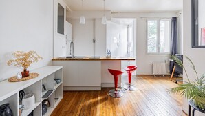 Eine moderne Küche mit einer zentralen Kochinsel, weißen Schränken und einem Fenster für natürliches Licht.