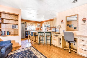 A kitchen with wooden cabinets, a microwave, and a bar area with stools.