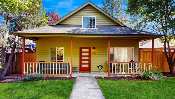 A two-story house with a front porch, a red door, and a mailbox. - Beautiful home with patio - in the perfect location near Downtown Bend & more (Bend)
